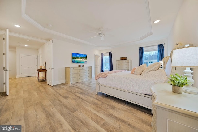 bedroom with light wood finished floors, a raised ceiling, crown molding, and recessed lighting