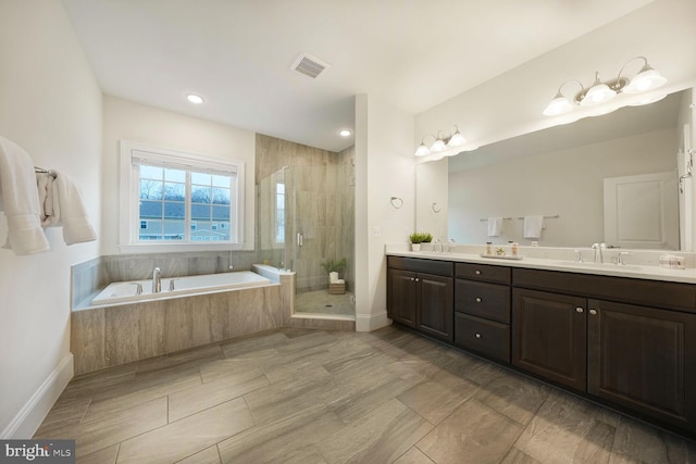 full bathroom with double vanity, a stall shower, visible vents, a garden tub, and a sink