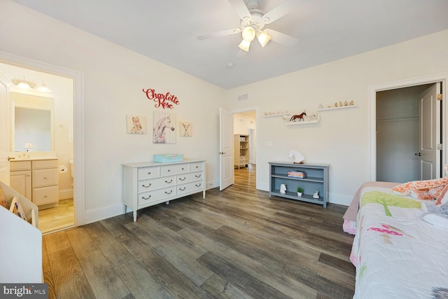 bedroom with baseboards, connected bathroom, visible vents, and wood finished floors