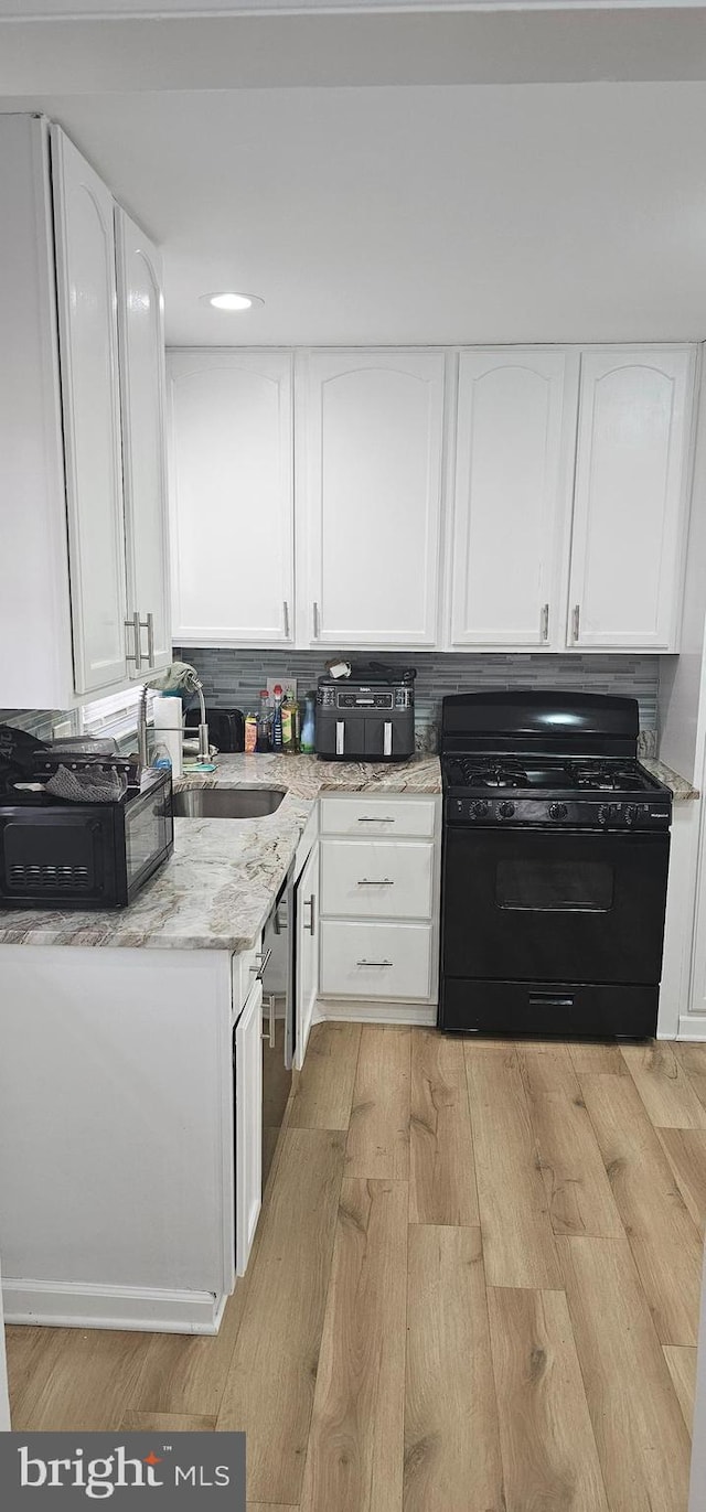 kitchen featuring white cabinetry, black appliances, and light wood-style floors