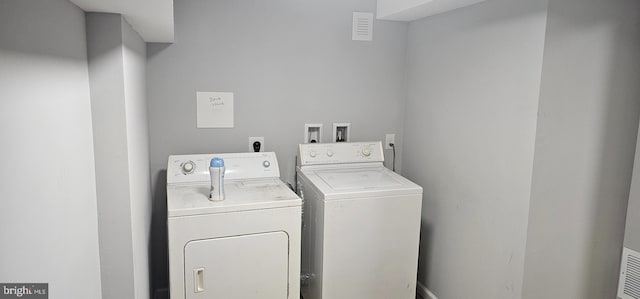 clothes washing area with visible vents and separate washer and dryer