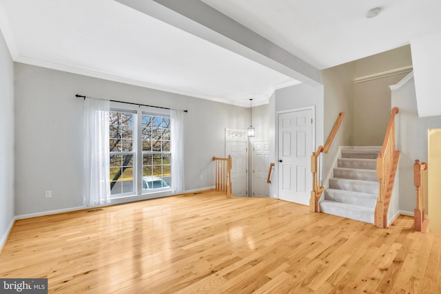 interior space with wood finished floors, visible vents, baseboards, ornamental molding, and stairway