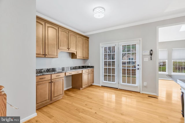 kitchen with ornamental molding, light wood finished floors, built in study area, and baseboards