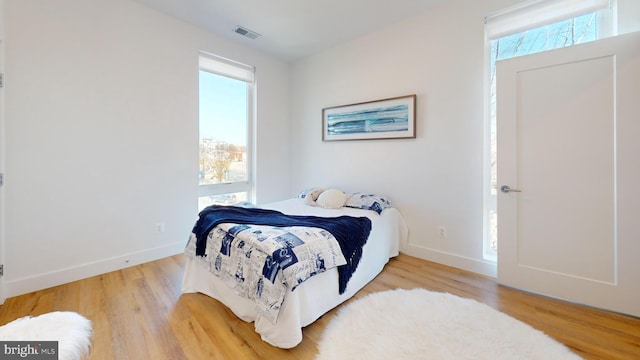 bedroom featuring wood finished floors, visible vents, and baseboards