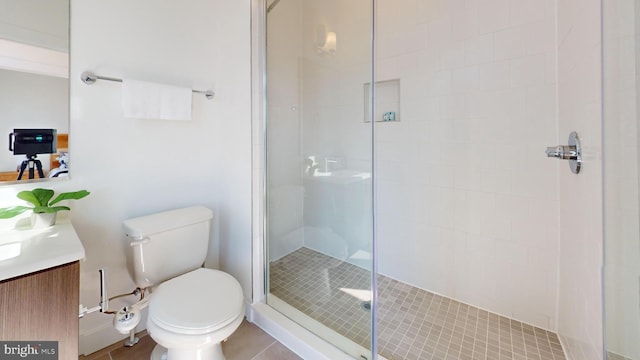 bathroom featuring tile patterned floors, toilet, tiled shower, and vanity