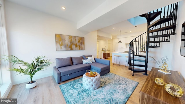 living area with recessed lighting, baseboards, stairs, and light wood-style floors