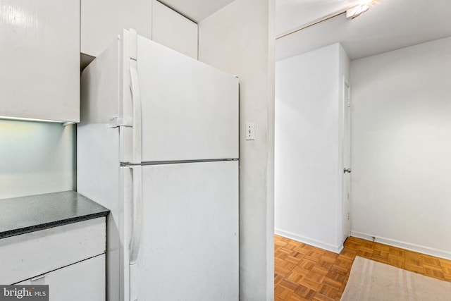 kitchen featuring baseboards, white cabinetry, and freestanding refrigerator