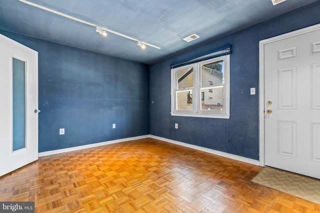 empty room featuring rail lighting, baseboards, and visible vents