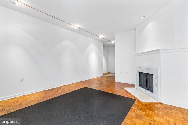 unfurnished living room with a premium fireplace, baseboards, and track lighting