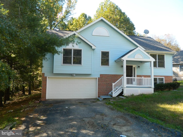 split foyer home featuring driveway, a garage, and brick siding