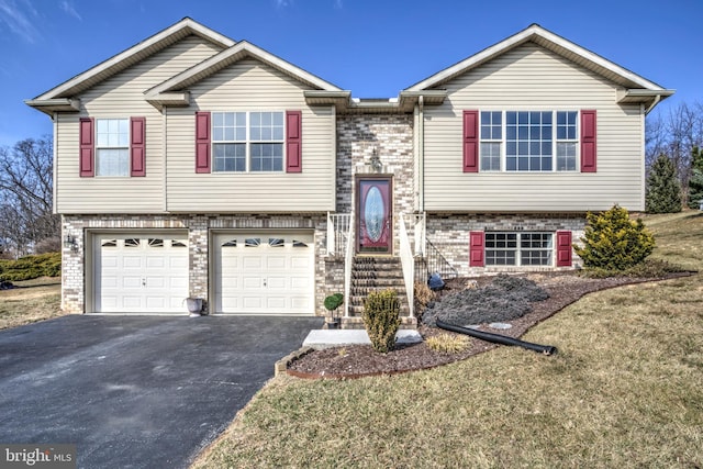 split foyer home with a garage, driveway, and brick siding