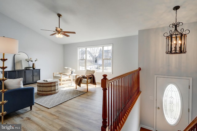 foyer with ceiling fan with notable chandelier, lofted ceiling, and wood finished floors