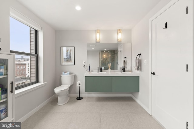 full bathroom with double vanity, toilet, baseboards, and a sink