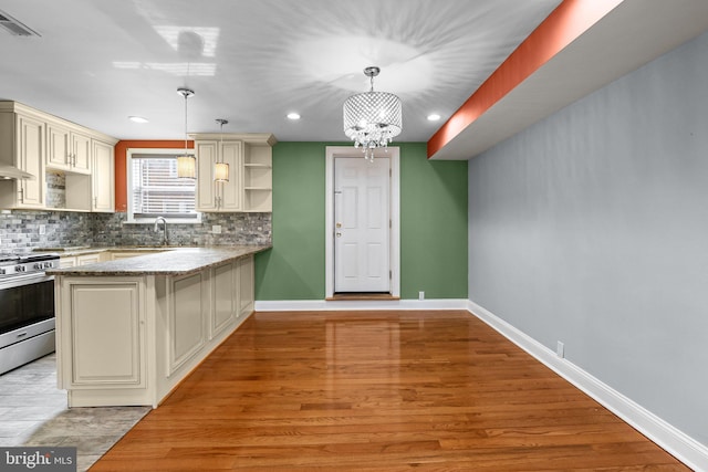 kitchen with cream cabinetry, open shelves, tasteful backsplash, gas stove, and baseboards