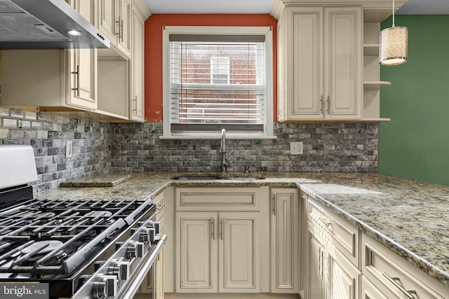 kitchen with gas stove, a sink, under cabinet range hood, and cream cabinets