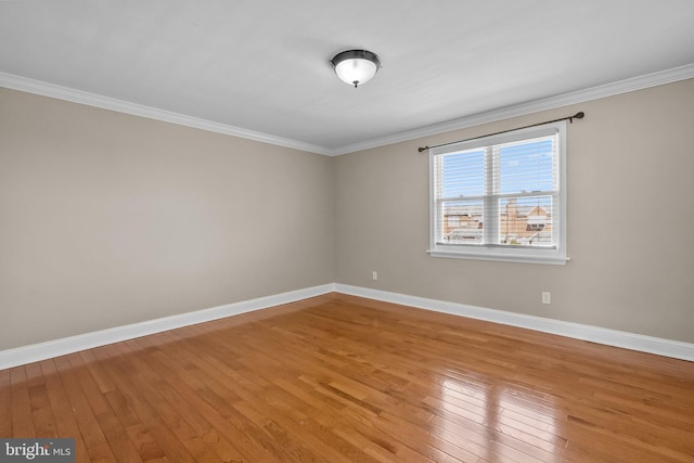 spare room featuring light wood-style floors, ornamental molding, and baseboards