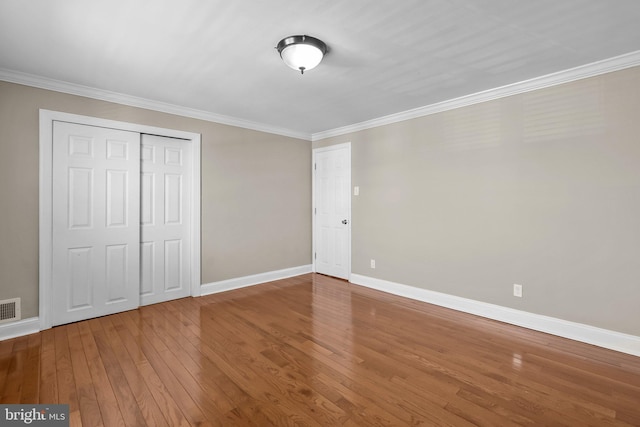 unfurnished bedroom featuring visible vents, crown molding, baseboards, and hardwood / wood-style flooring