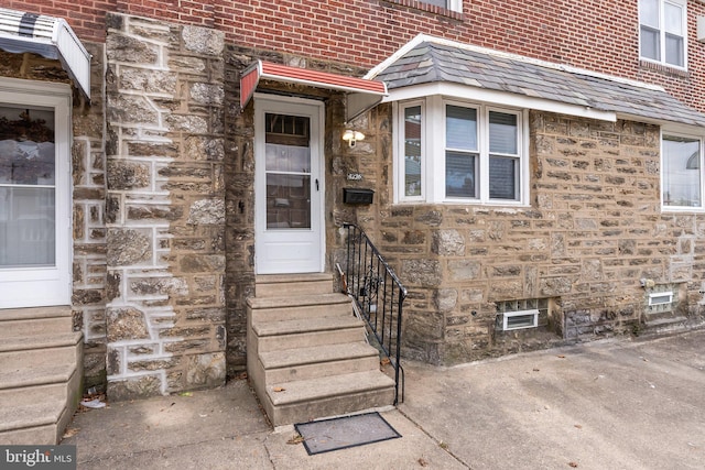 doorway to property featuring stone siding and brick siding