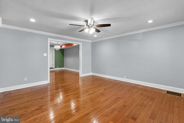 unfurnished room with baseboards, hardwood / wood-style floors, visible vents, and crown molding