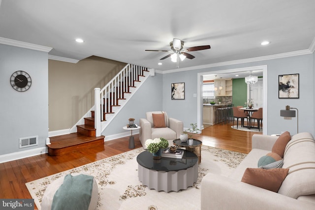 living room featuring ornamental molding, visible vents, stairway, and wood finished floors