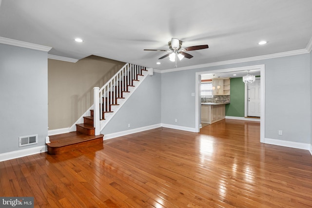 unfurnished living room featuring wood-type flooring, stairs, visible vents, and crown molding