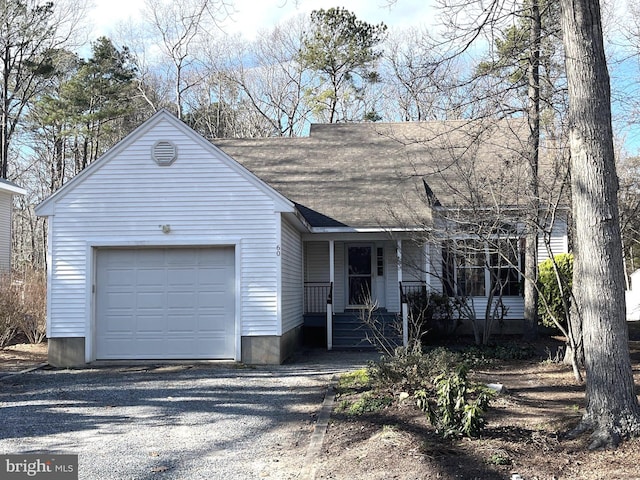 view of front of property with a porch, roof with shingles, an attached garage, and gravel driveway