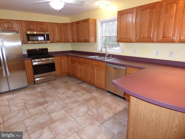 kitchen with dark countertops, appliances with stainless steel finishes, brown cabinets, and a sink