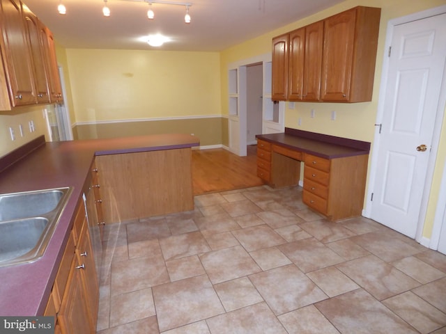 kitchen with dark countertops, brown cabinetry, built in study area, a sink, and a peninsula