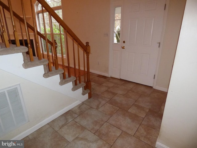 foyer entrance with visible vents, baseboards, and stairs