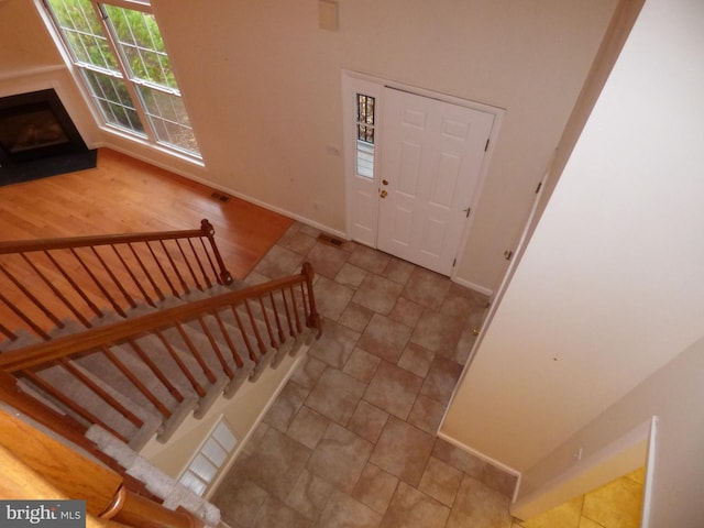 entryway with baseboards, a fireplace, stairway, and visible vents