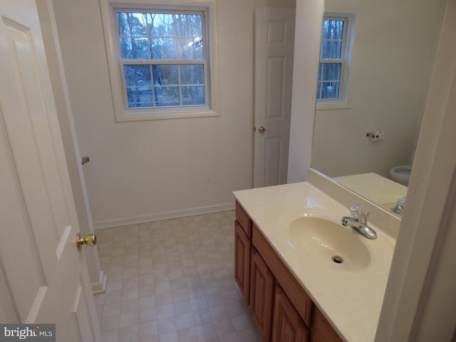 bathroom with toilet, vanity, and baseboards