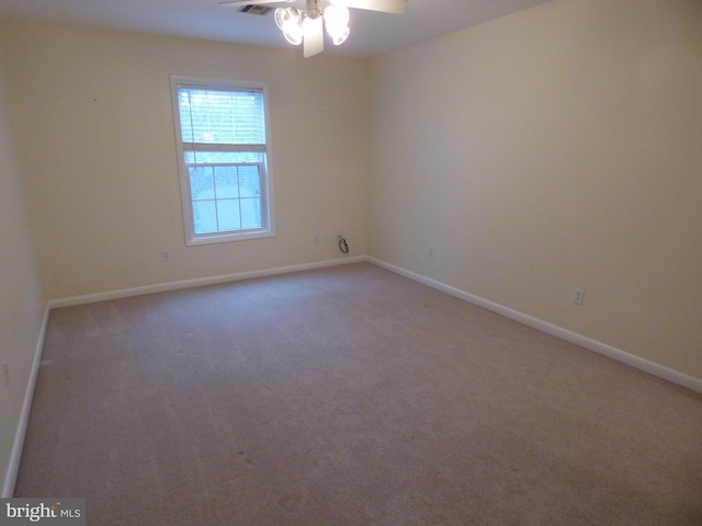 carpeted spare room featuring baseboards and a ceiling fan