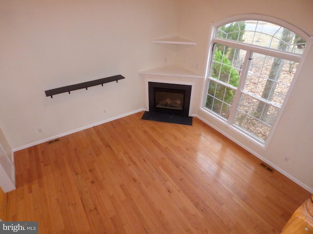 unfurnished living room with visible vents, a fireplace with flush hearth, and light wood-style flooring