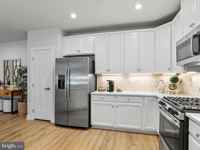 kitchen with stainless steel appliances, light wood finished floors, white cabinetry, and tasteful backsplash