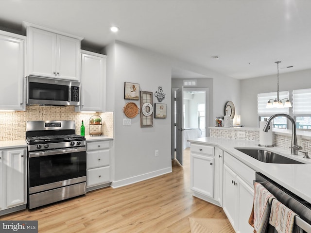 kitchen featuring decorative backsplash, stainless steel appliances, light countertops, light wood-type flooring, and a sink