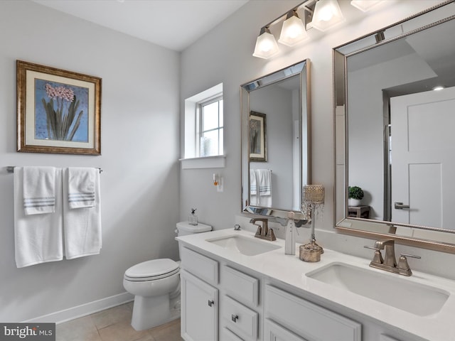 bathroom featuring toilet, tile patterned flooring, double vanity, and a sink