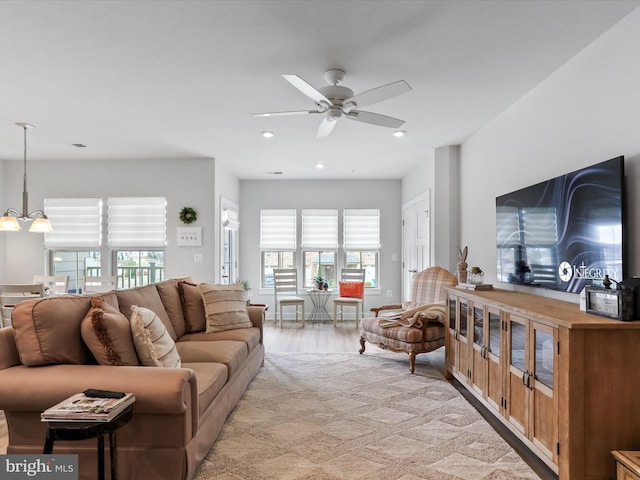 living area with light wood-style floors, recessed lighting, visible vents, and ceiling fan with notable chandelier