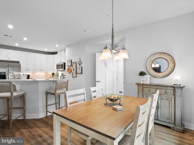 dining room featuring a chandelier, wood finished floors, visible vents, and recessed lighting