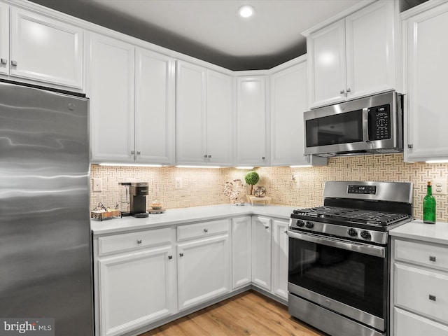 kitchen with light wood finished floors, tasteful backsplash, light countertops, appliances with stainless steel finishes, and white cabinetry