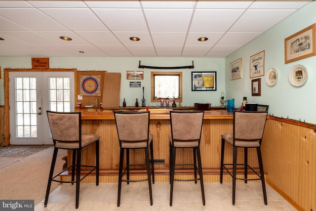 bar with french doors, a paneled ceiling, and wet bar