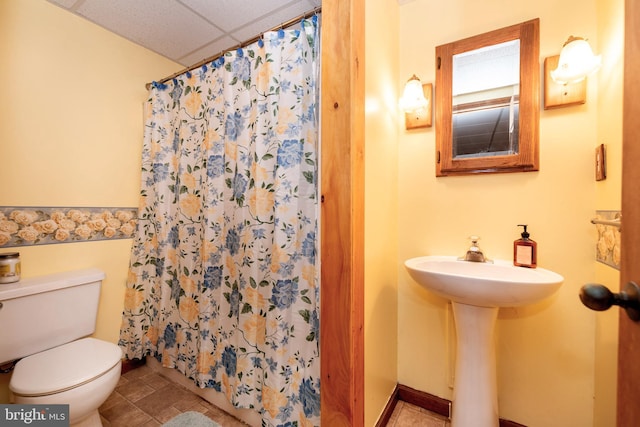 full bathroom featuring a paneled ceiling, curtained shower, a sink, and toilet