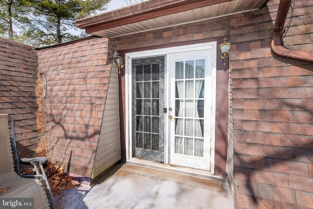 view of exterior entry with a shingled roof