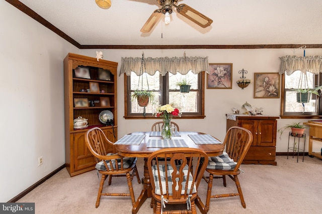 dining room featuring ornamental molding, light colored carpet, ceiling fan, and baseboards