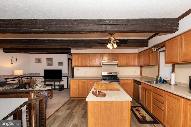 kitchen with stainless steel appliances, light countertops, a sink, a kitchen island, and under cabinet range hood