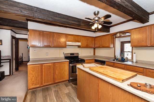 kitchen featuring under cabinet range hood, stainless steel appliances, a sink, light countertops, and beam ceiling