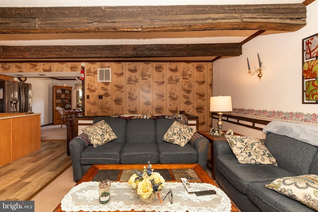 living area featuring beamed ceiling, wood finished floors, and visible vents