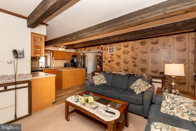 living area with a ceiling fan, a textured ceiling, visible vents, and beam ceiling