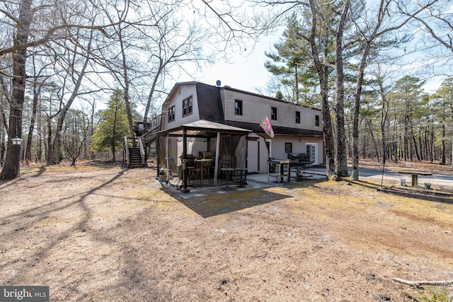 back of property with stairs, a patio, a gazebo, and a gambrel roof