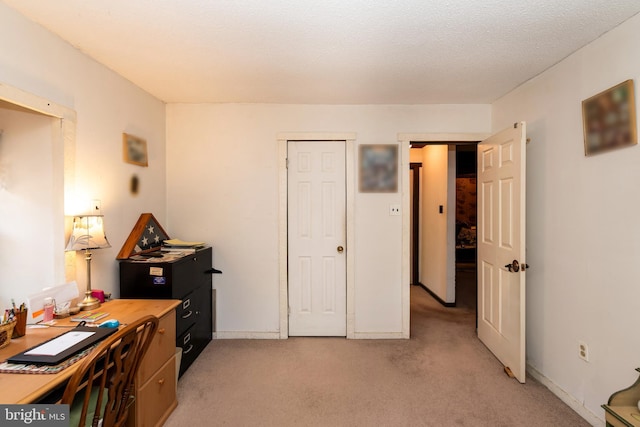 home office featuring light carpet, a textured ceiling, and baseboards