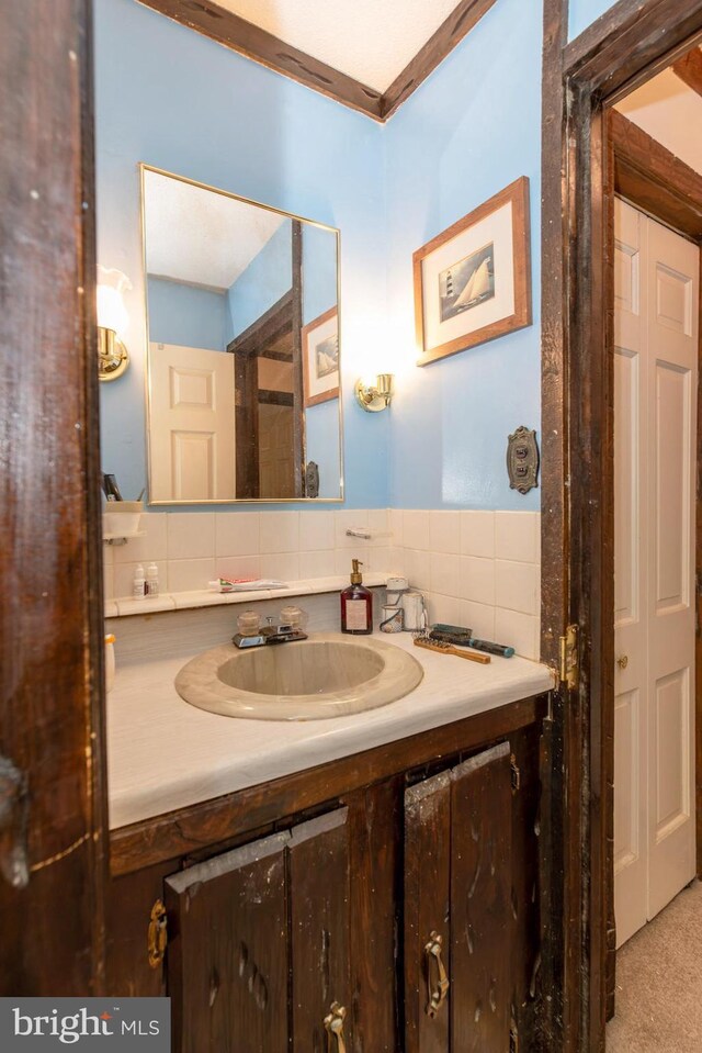 bathroom featuring crown molding, tasteful backsplash, vanity, and tile walls